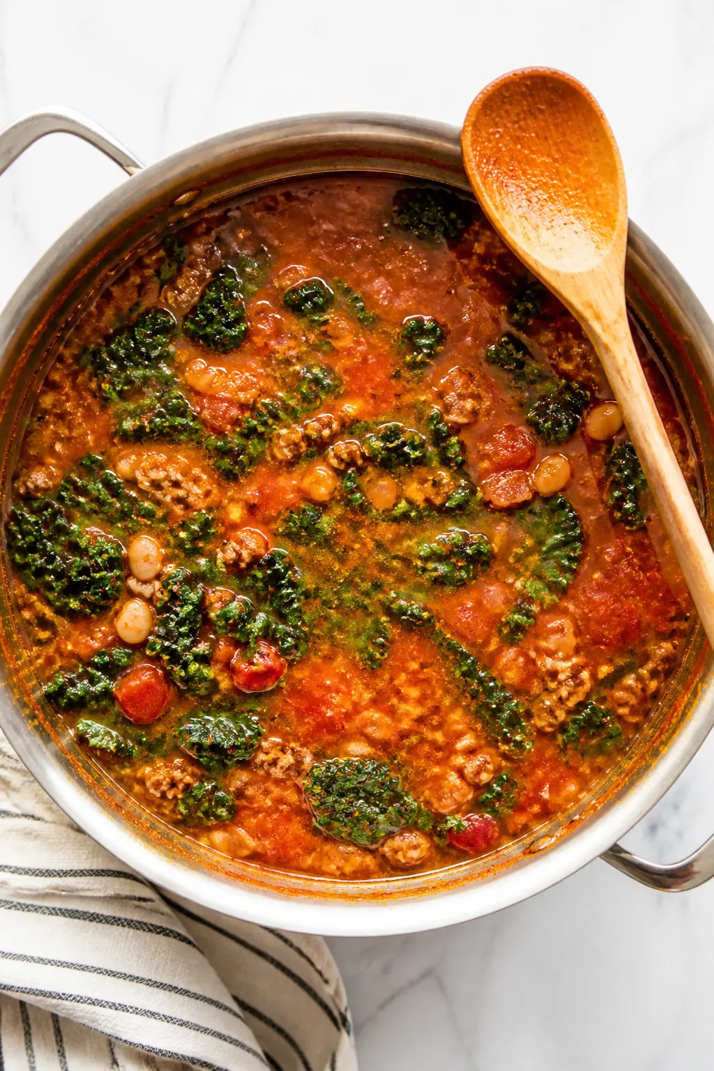 Cooking process: Overhead shot of the soup mid-cook in a wide stainless pot right after adding green