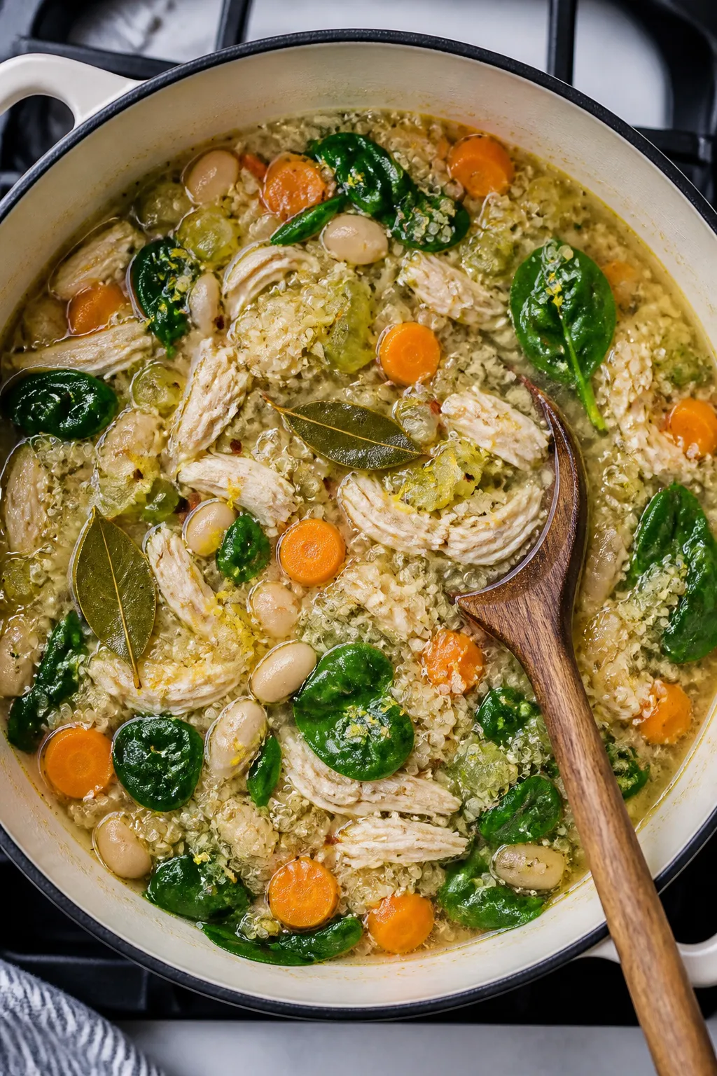 Cooking process, overhead: Simmering high-protein chicken soup in a Dutch oven mid-cook with quinoa